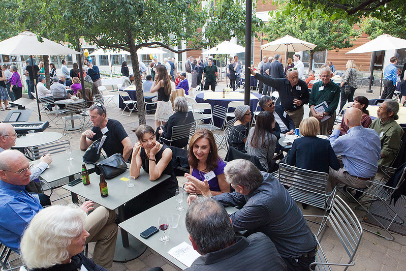 A group of people gather in the King Hall courtyard at many small tables.