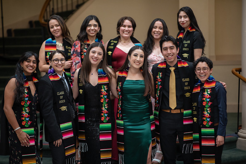 Students wearing graduate stoles gather.