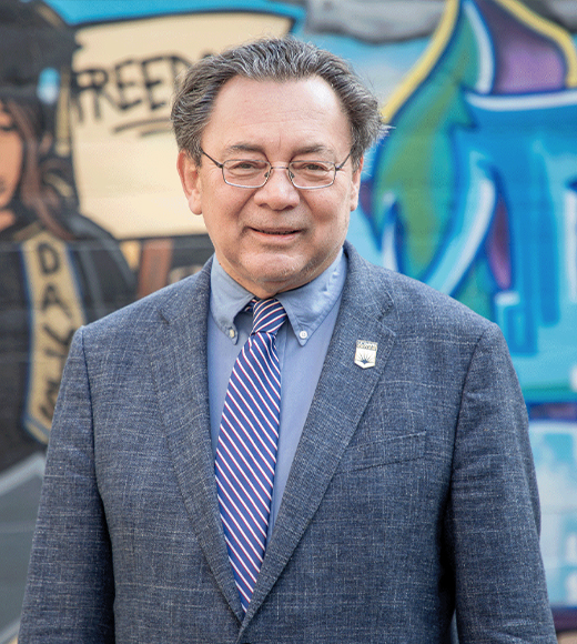 Dean Kevin R. Johnson in the King Hall courtyard  in front of a mural.