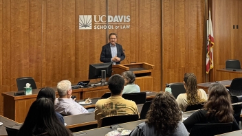 Speaker at podium in UC Davis School of Law courtroom-style classroom with seated audience