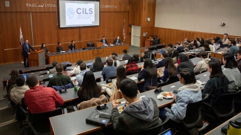 Lecture hall, speaker at podium and rows of seated students (photo)