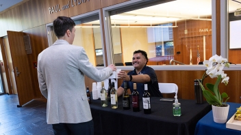 Smiling staffer pours wine for a guest at indoor tasting table