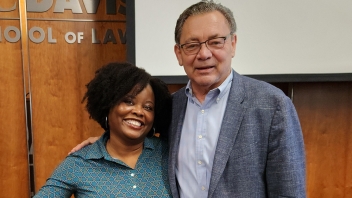 Smiling woman and man standing before a law school sign