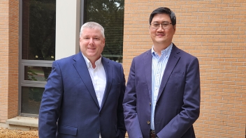 Two men in suits smiling outside a brick building