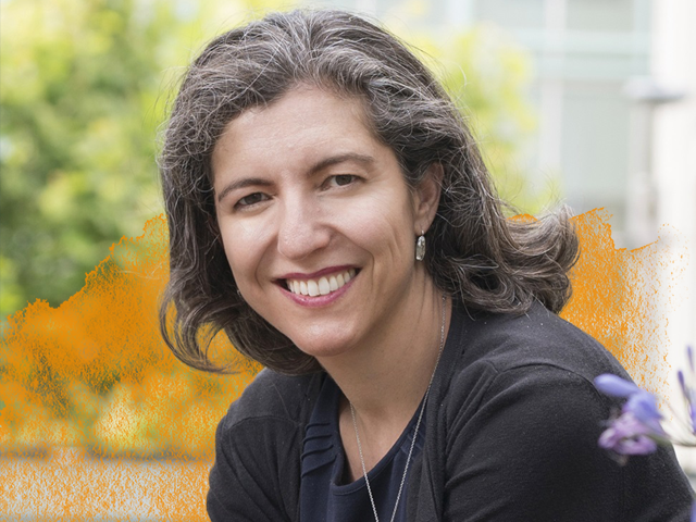 Professor Chimène Keitner wearing a grey shirt and smiling at the camera with a yellow haze in the background.