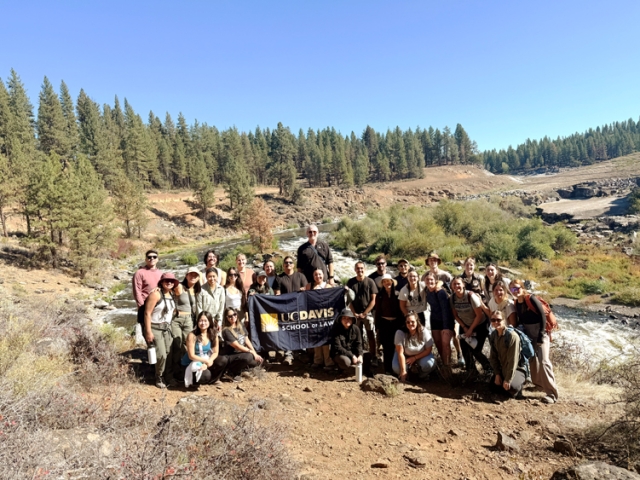 UC Davis Law Cases and Places students standing on a mountaintop, holding a UC Davis Law banner.