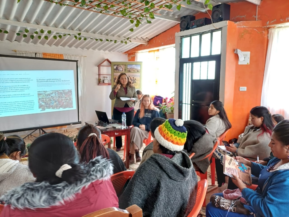 A group of women listen to a presentation in a large room.