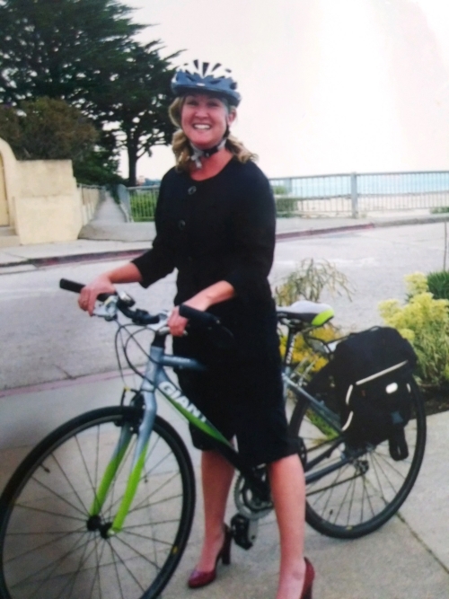 In this archival photo, Dove Cassman wears a black dress, bike helmet and high heels while pictured with her bicycle on the way to work. 