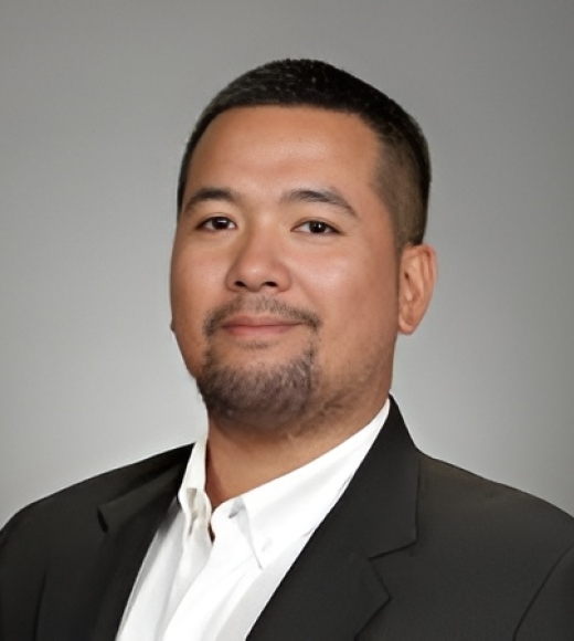 Professional portrait of a man in a suit with a neutral background.
