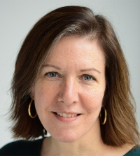 Professor Hannah Buxbaum smiling softly in front of a white background.