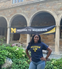 Sijay, a student who participated in KHOP and is posing in front of a brick building with a University of Michigan sign.