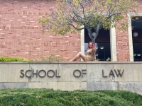 Christina Đặng, a KHOP graduate posing in front of a "School of Law" sign at UCLA.