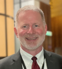 Charles "Dom" Ayotte, Associate Director of Career Services, wearing a suit and smiling.