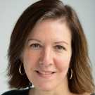 Professor Hannah Buxbaum smiling softly in front of a white background.
