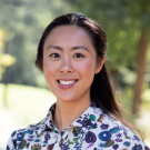 Clarisa P. Sudarma, lecturer at UC Davis School of Law, wearing a white and blue blouse while smiling. 