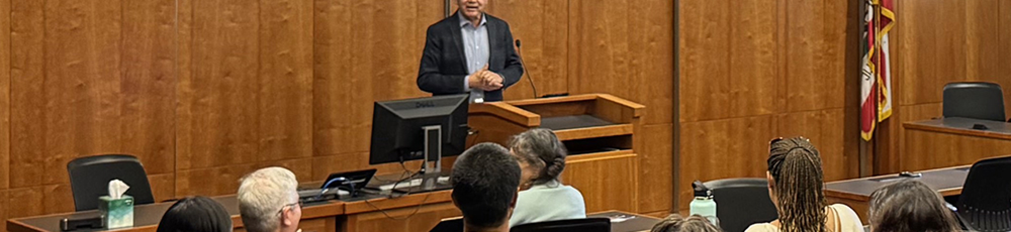 Speaker at podium in UC Davis School of Law courtroom-style classroom with seated audience